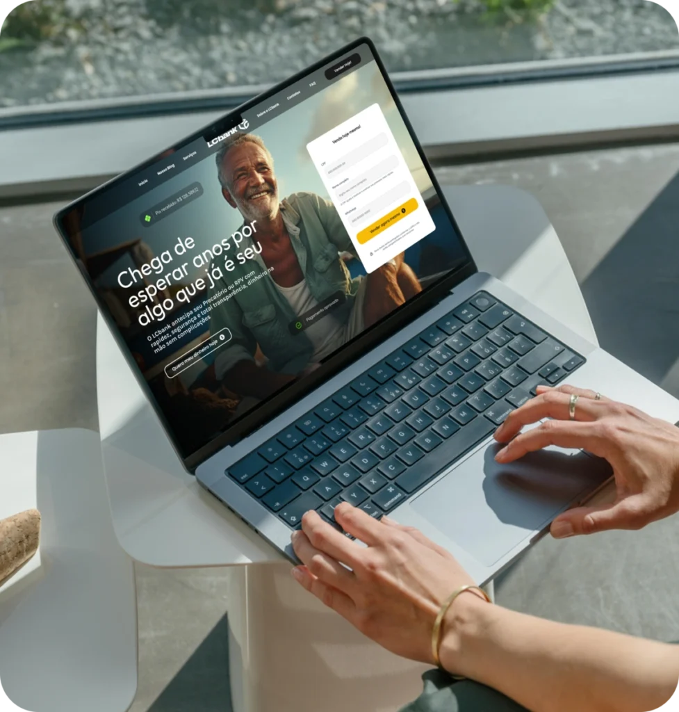 Pessoa digitando em laptop com LCbank no monitor e texto em português