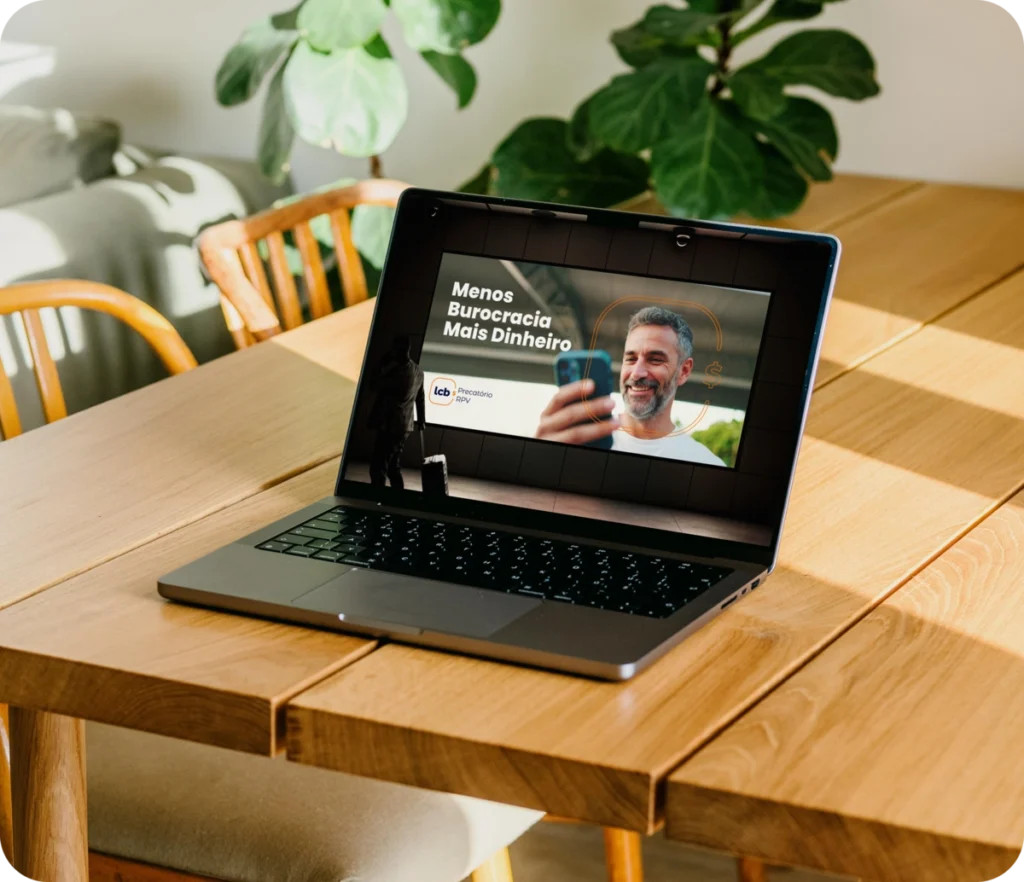 Laptop aberto exibindo vídeo sobre LCbank: Menos Burocracia, Mais Dinheiro.